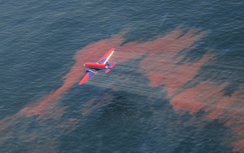 An aircraft applies dispersants over a slick of sunlight-weathered oil in the waters of the Gulf of Mexico.
